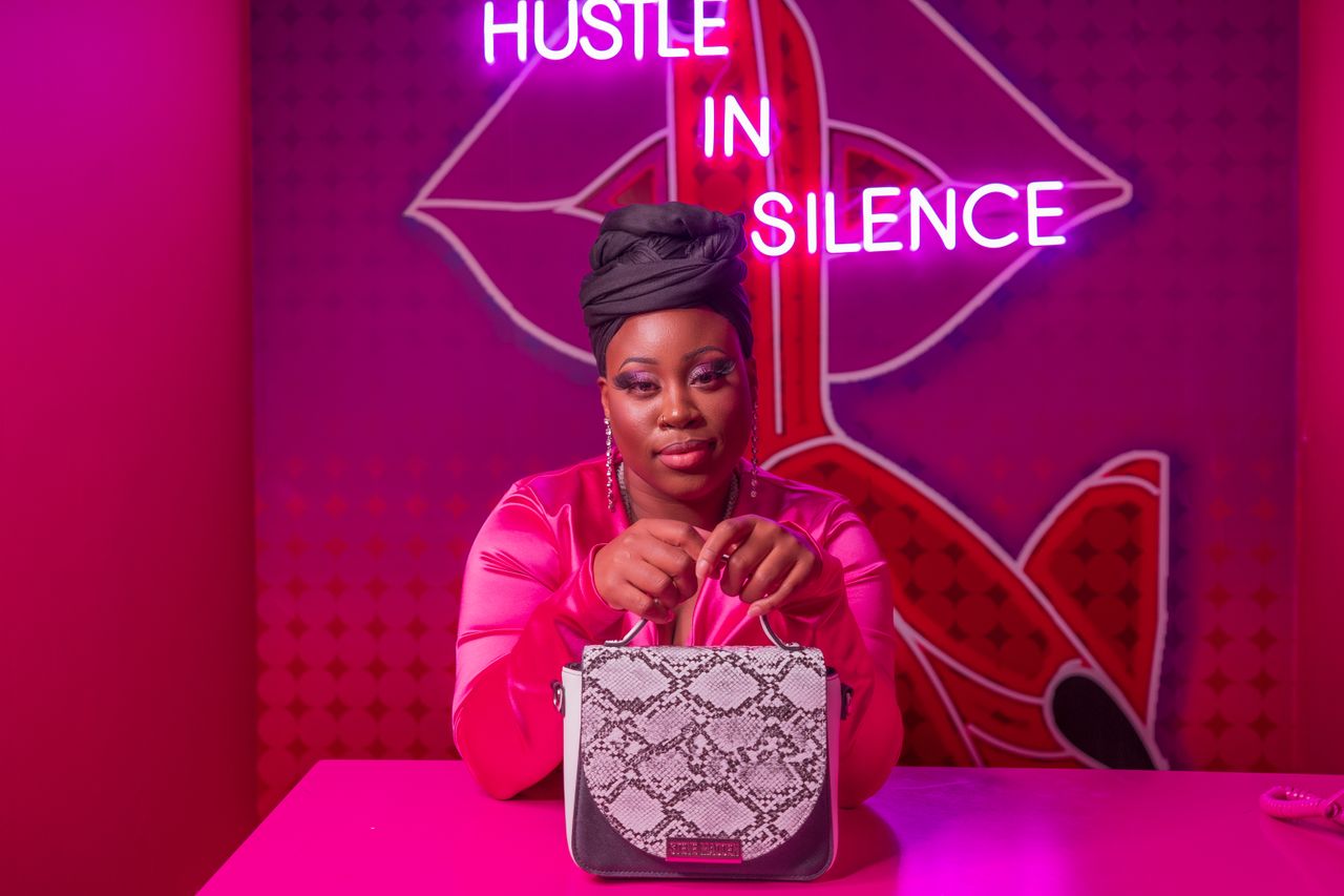 about-us-01 A fashionable woman in a striking neon-lit environment, holding a snake print handbag. Perfect for lifestyle and fashion themes.