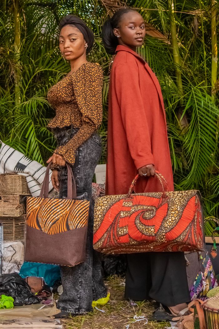 about-us-02 Two stylish women showcasing colorful African print bags in a rich, natural setting.